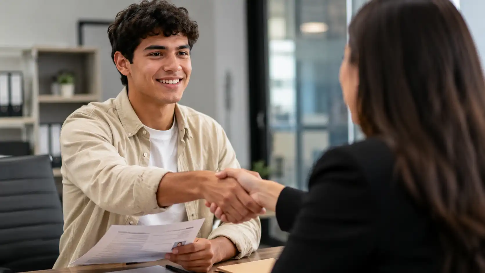 Joven colombiano consigue su primer empleo durante una entrevista laboral en una empresa moderna.